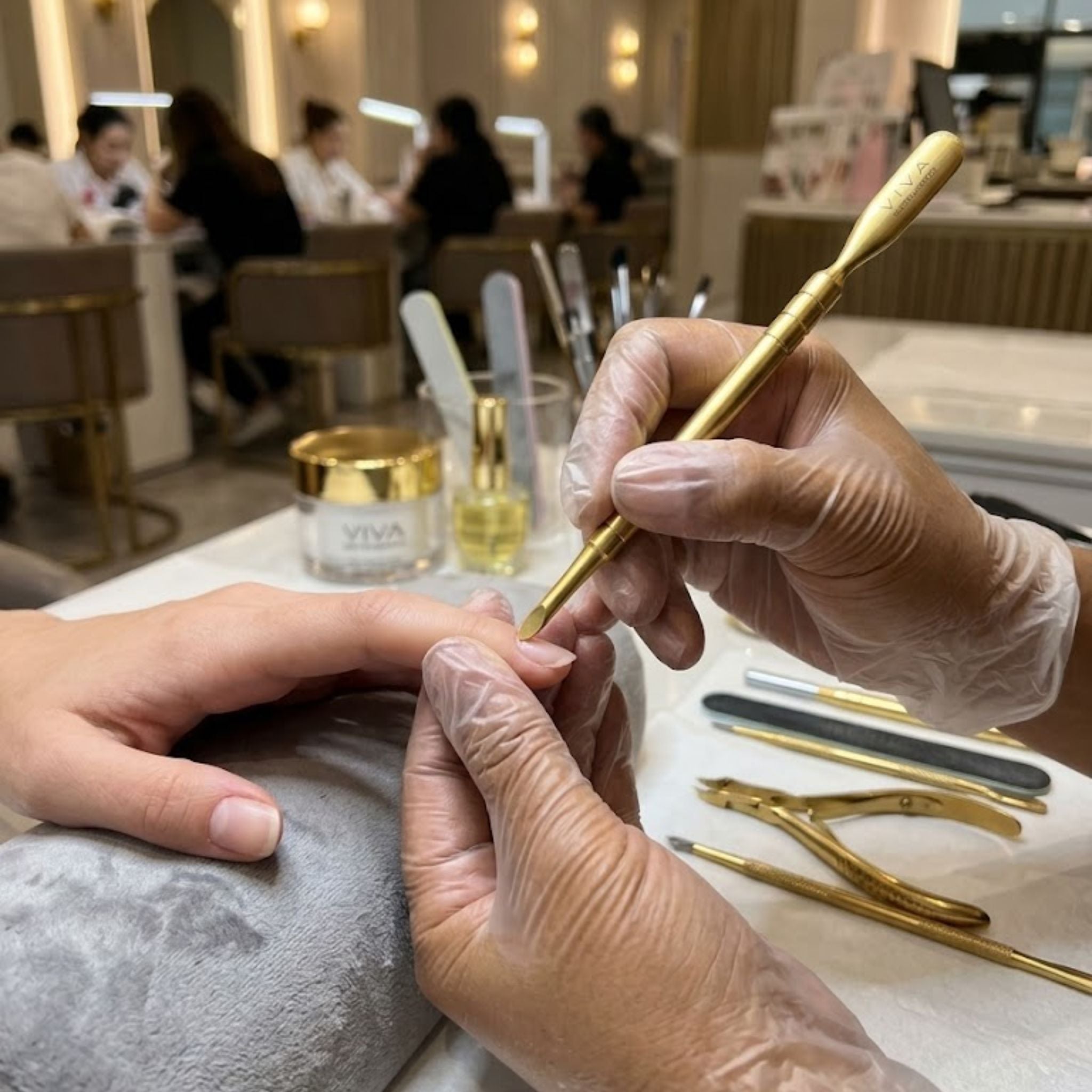 cuticle nail pushers Nail technician applying gold polish to a client's nails in a nail salon - viva instruments