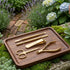 Set of gold nail care tools on a wooden tray with a garden background - viva instruments