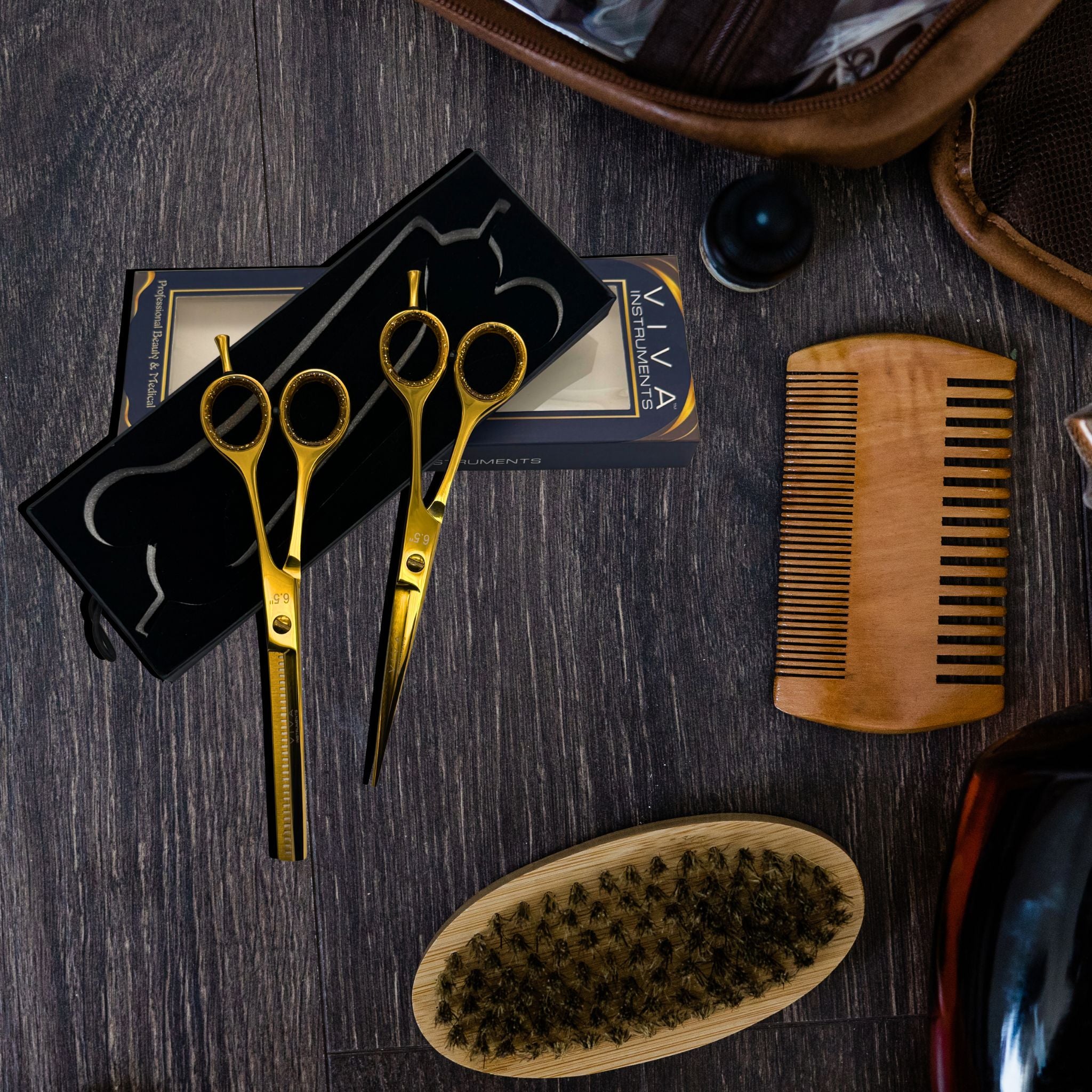 Set of gold scissors, wooden comb, and brush on a dark wooden surface with VIVA brand visible.