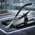 A pair of precision metal nail scissors with black handles, resting on a black display stand on a dark work surface with a glowing circular light border. Viva Instruments 