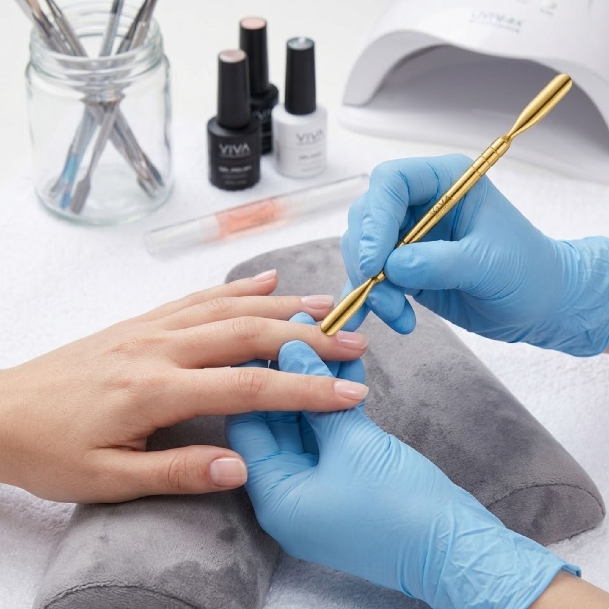 Nail technician applying nail cuticle pushers to a client's nails with VIVA nail polish bottles in the background.