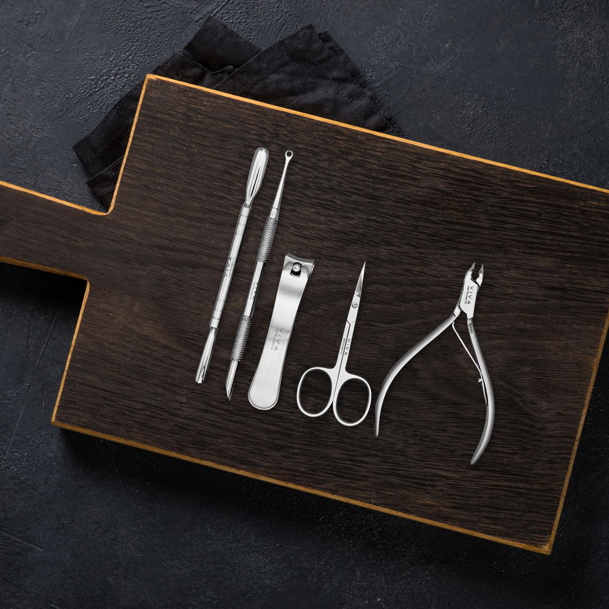 Set of nail care tools on a wooden board with a black background - viva instruments 